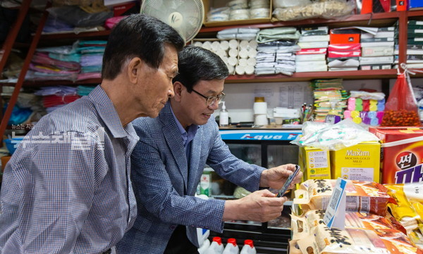 ▲김돈곤(오른쪽) 청양군수가 한 상점에 들러, 휴대폰을 이용한 모바일 상품권을 사용하고 있다. 사진=청양군