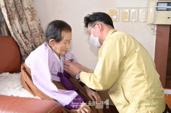 ▲김정섭(시장)이 99세 강춘화어르신께 꽃을 달아드리고 있다. 사진=공주시
